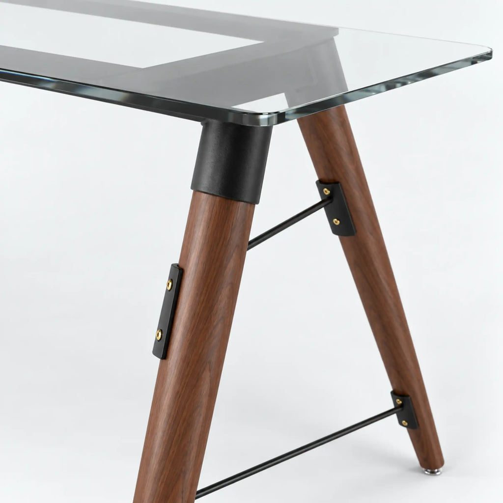 Close-up of the Fexon dining table showing its clear top edge, brown legs and black connecting brackets.
