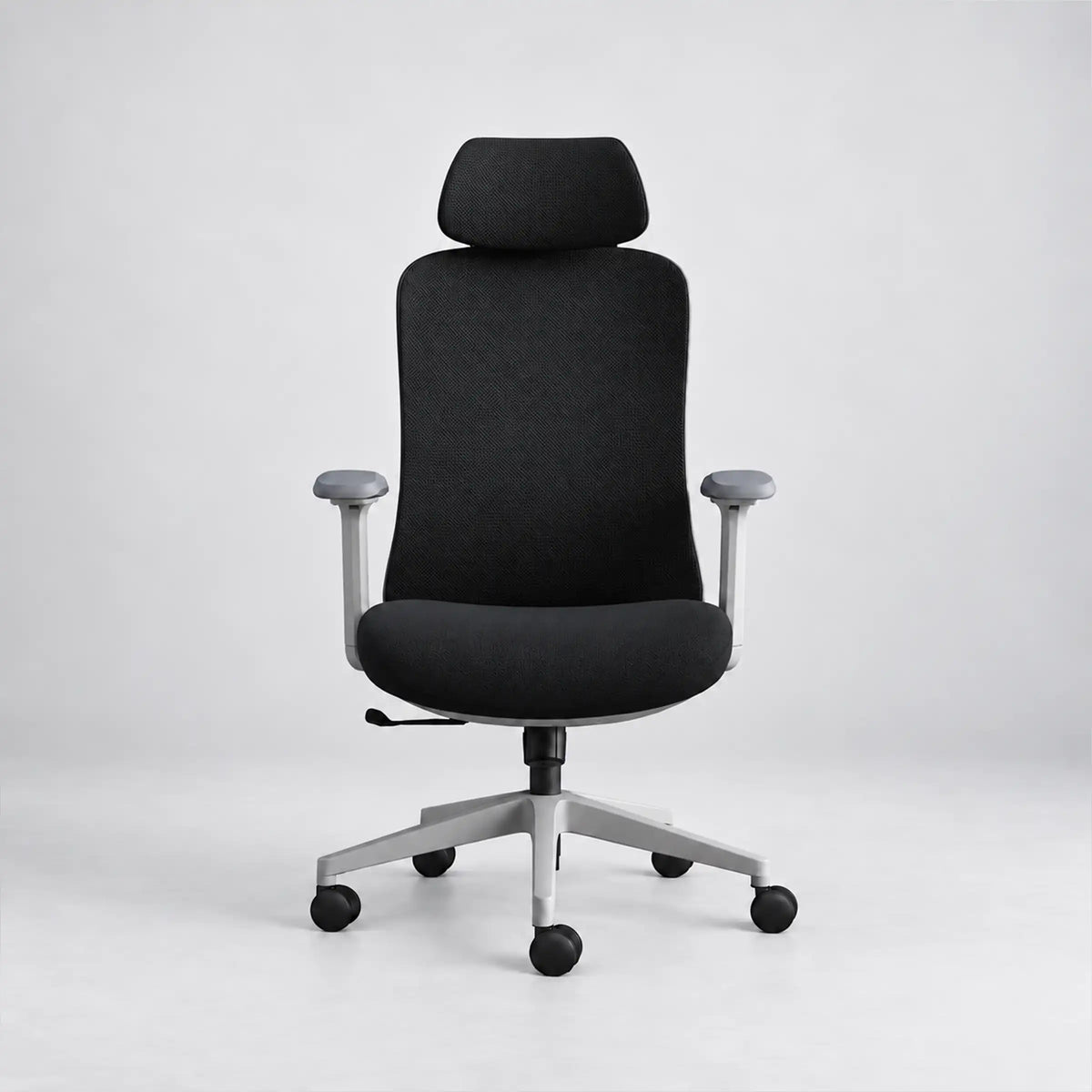 A modern black fabric office chair with a high back, adjustable armrests, and a silver five-star wheeled base, photographed against a seamless light gray studio background.